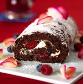 Chocolate roll with berries and icing sugar