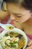 Woman eating Asian glass noodle soup