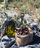 Eine Flasche Olivenöl, Nizzaer Oliven in einer Holzschale