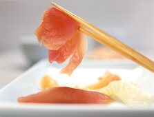 A piece of raw fish on chopsticks (Sashimi sushi)