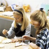 Two girls painting Christmas biscuits