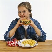 Modell isst Hamburger mit Pommes