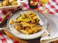 Wiener schnitzel with lemon wedges and fried potatoes