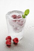 Ice glass with clear schnapps and raspberries