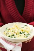 Woman holding plate of tortellini with spinach & cream sauce
