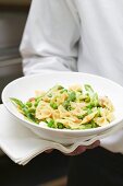 Waiter serving farfalle with vegetables