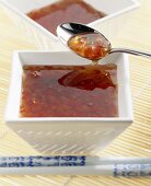 Spicy chilli sauce in bowl and on spoon