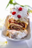 Raspberry roulade with icing sugar, partly sliced