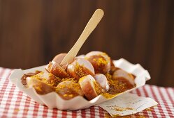 Currywurst (sausage with ketchup & curry) in paper dish, bill