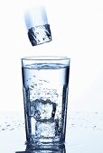 Ice cube falling into a glass of mineral water