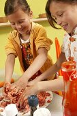 Two girls mixing minced meat with ketchup