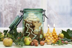 Spekulatius (German Christmas shortcrust biscuits) in a preserving jar with candles, apples and nuts