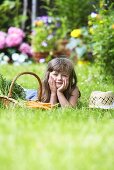 Kleines Mädchen neben Korb mit Möhren im Garten