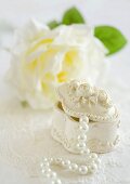 Jewellery box with a pearl necklace in front of a white rose