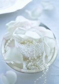 Decorative casket with a string of pearls and white rose petals