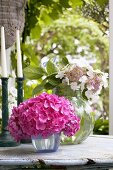 Hortensien in Glasvasen auf Gartentisch