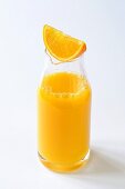 Orangenschnitz auf Flasche mit Orangensaft