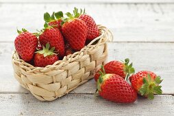 Several strawberries in and beside small basket