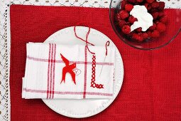 Raspberries with whipped cream beside plate with napkin