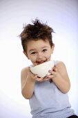 Small boy licking out bowl