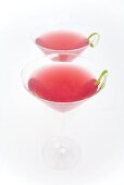 Two Cosmopolitan cocktails with lime peel