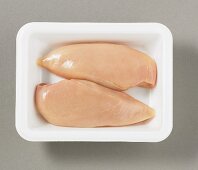 Two chicken breast fillets on plastic tray