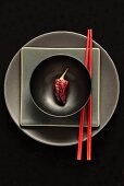 Dried chilli in black bowl on plates with chopsticks