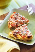 Two pieces of courgette and tomato tart with pine nuts