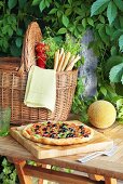 Vegetable pizza, melon and basket with grissini and herbs