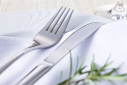 Knife and fork on fabric napkin with rosemary sprig