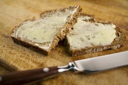 Slice of bread and butter, cut in half, with knife