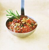 Tomato sauce with bacon, mushrooms and rosemary on ladle