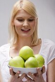 Blond woman holding dish of green apples