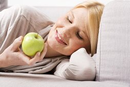 Blonde Frau hält grünen Apfel