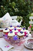 Cupcakes with violets on cake stand, tea