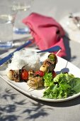 Barbecued kebabs with rice and salad leaves