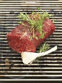 Beef fillet with herbs and garlic on barbecue rack