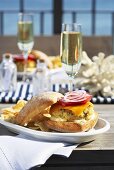 A fish burger and a glass of champagne on a table overlooking the sea