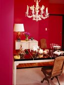 Feminine dining room with pretty chandelier and period furniture surrounded by magenta walls