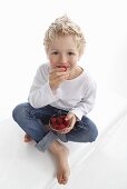 A little boy eating fresh raspberries