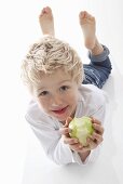A little boy holding a half eaten apple