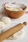 Dough with rolling pin and in bowl half-covered by tea towel