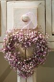 Heart-shaped wreath of pink baby's breath on doorknob