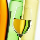 Glass of white wine in front of wine bottles