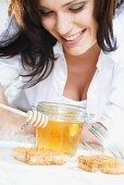 Young woman with honey, honey dipper and honeycomb