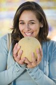 Young woman holding a netted melon in her hands