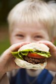 Kleiner Junge hält einen Burger