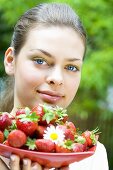 Young woman holding a dish of strawberries