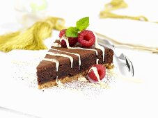 A piece of chocolate fudge cake with raspberries