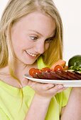 Young girl looking at plate of vegetables in her hands